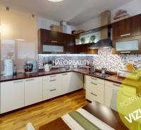 Spacious kitchen in a 2-room apartment with a wooden decor floor and white cabinets.