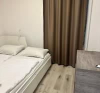 A bedroom in a holiday apartment with brown curtains and a wooden decor floor.