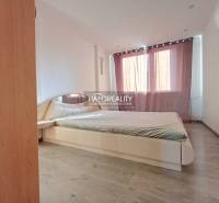 Bedroom with a comfortable bed in a 3-room apartment, floor with wood decor, curtains.