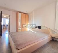 A bedroom with a built-in wardrobe, bed, and wooden decor flooring in a 3-room apartment.