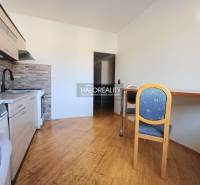 A kitchen in a 3-room apartment with a wooden decor floor and a dining table.