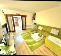 Living room with a sofa and wood-patterned flooring in a three-room apartment.