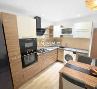 A kitchen in a 3-room apartment with wood decor, appliances, and a dining table.