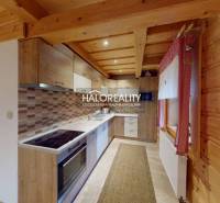 A kitchen in a cottage with wooden ceilings, wooden decor, and rustic accessories.