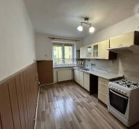 A kitchen in a 2-room apartment with a gas stove and a floor with a wooden decor.