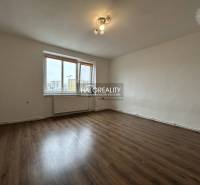 A room in a 2-bedroom apartment with a wooden decor floor and a large window.
