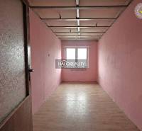 A narrow room with light pink walls and a wooden decor floor in a family house.