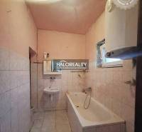 Bathroom with a bathtub and sink in a family house with white tiles.