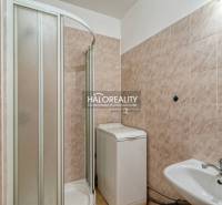 Bathroom in a 2-room apartment with a sink, shower, and washing machine.