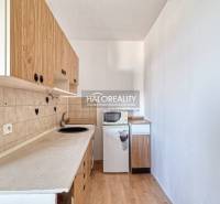 Kitchen in a 2-room apartment with wooden decor, cabinets, and refrigerator, interior.