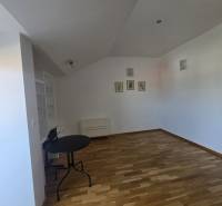 A room in a recreational apartment with a wooden decor floor, a table, and a shelf.