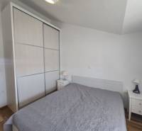 A bedroom of a holiday apartment with a large wardrobe and a wooden decor floor.