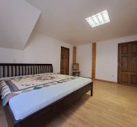 A bedroom with wood-patterned flooring, a bed, and a large mirror in a three-room apartment.