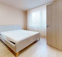 Bedroom with a bed and light wood-patterned flooring in a 3-room apartment.