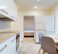 A kitchen in a three-room apartment with a white kitchen unit and a dining table.