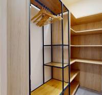 A wardrobe with a wooden decor in a 3-room apartment with a shelving system and hangers.