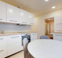A kitchen with white cabinets and a round table in a 3-room apartment.