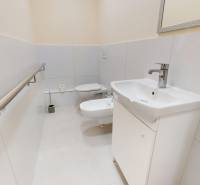 A bathroom with a sink, toilet, and bidet in a 3-room apartment, with white tiles.