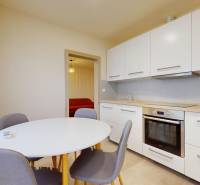 A kitchen with a table and gray chairs in a 3-room apartment, light cabinets and appliances.