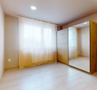 A bright room with a large mirrored wardrobe and a floor with a wooden decor.