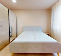 A bedroom in a 3-room apartment with a bed and a wardrobe with a wooden decor.