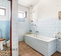 Bathroom with a bathtub, toilet, sink, and window in a family house.