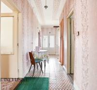 A hallway in a family house with patterned wallpaper and tiles, a table with a tablecloth.