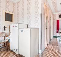 A hallway with a refrigerator and decorative wallpaper in a country family house.