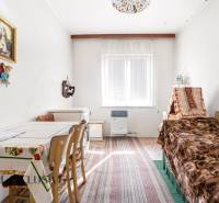 A room in a family house with a bed, a kitchen table, and wall decorations.