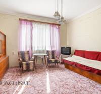 Living room in a family house with older furniture, a television, and a patterned carpet.