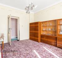 A room in a family house with display cabinets, a table, and a patterned carpet.