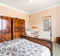 A bedroom in a family house with retro cabinets, a colorful carpet, and patterned wallpaper.