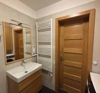 Bathroom with a sink, mirror, radiator, and cabinets in a 3-room apartment.