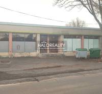 A single-story building with glass panels, in front of it are stands with containers. Commercial premises.