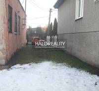 A narrow space between buildings with greenery and melting snow, suitable for commercial premises.