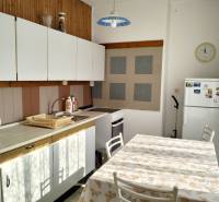 A kitchen in a 2-room apartment with a white kitchen unit and a dining table.