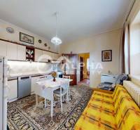 A dining room of a family house with a carpet, a colorful couch, and decorative plates on the wall.