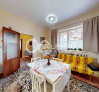A kitchen in a family house with carpets, furniture, and a yellow blanket on the sofa.
