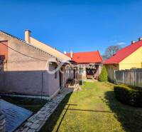 A family house in Spišské Vlachy with a yard, a stone path, and a metal roof.