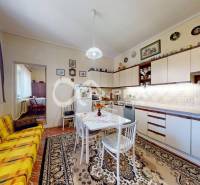 A kitchen in a family house with a dining table, a sofa, and decorative plates on the wall.
