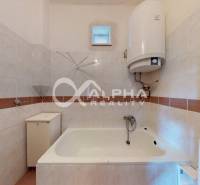 Bathroom with a white bathtub and tiles in a family house.