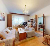 Living room in a family house with wood-patterned flooring, a sofa, and a cabinet set.