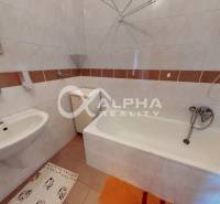 A bathroom with a bathtub and a sink in a family house with ceramic tiles.