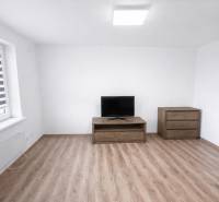Living room with a TV, drawer chest, and wooden decor flooring in a 2-room apartment.