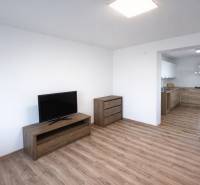 Living area of a 2-room apartment with a TV stand, drawers, and a floor with a wooden decor.