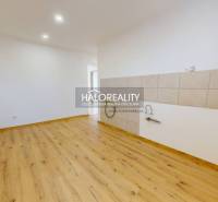 Bright kitchen in a 2-room apartment with a wooden decor floor and white walls.