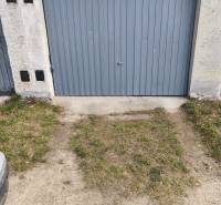 Garages on Kozmonautov Street in Martin with gray metal doors and a grassy edge.