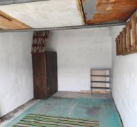 The interior of the garage includes a wooden cabinet, a rug, and empty shelves.