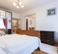A bedroom with a large wardrobe, wooden furniture, and a small crib in a 3-room apartment.