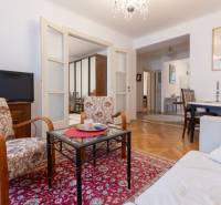 Living room in a 3-room apartment with carpets, floral armchairs, and a wooden decor floor.